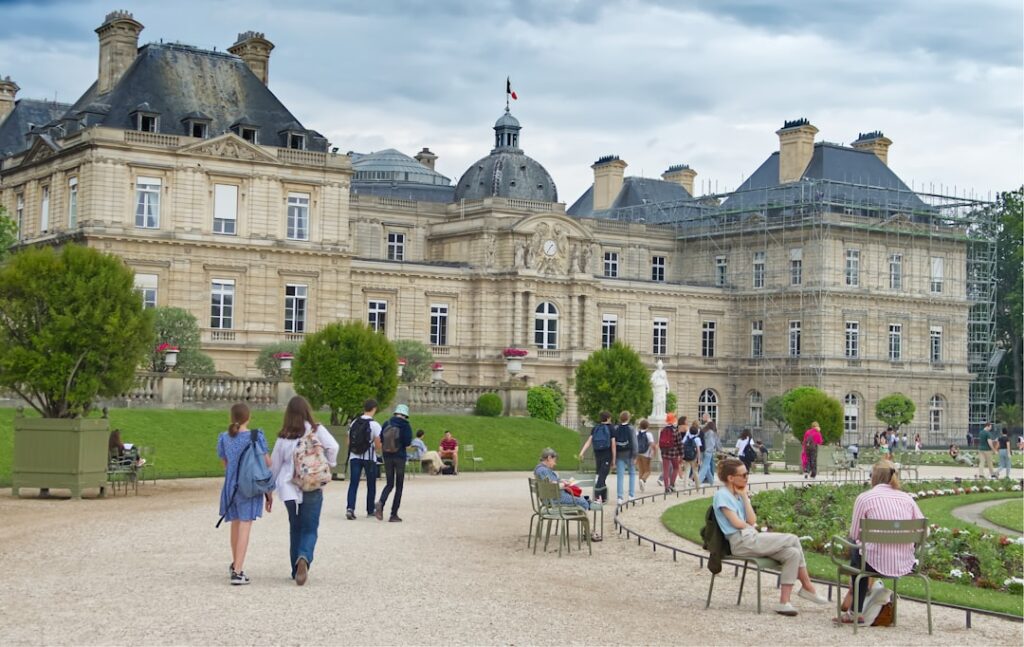 People stroll through a park in front of a palace.