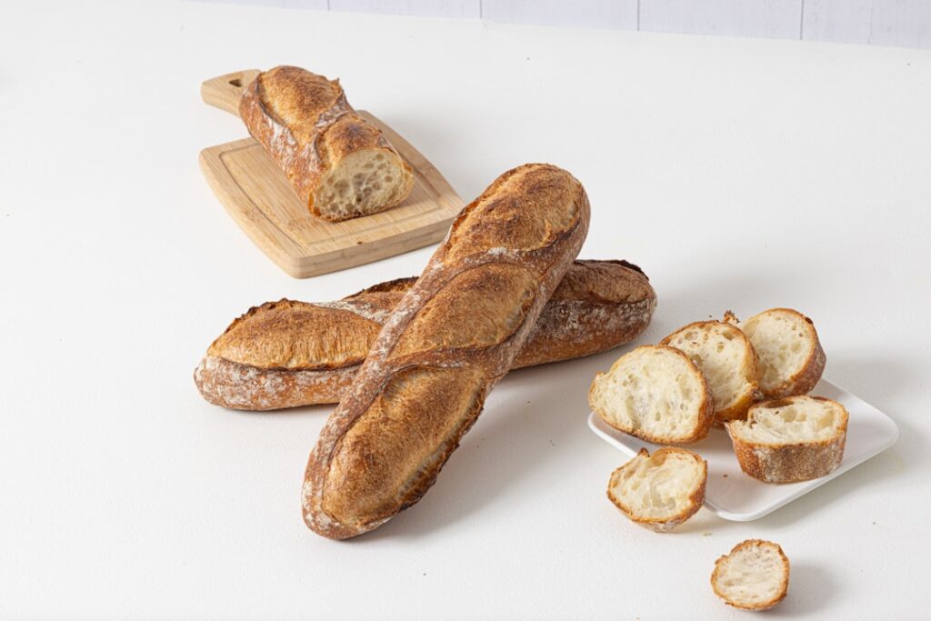 Freshly baked baguettes and slices on a white surface